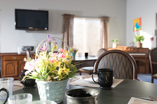 A cozy dining space illuminated by natural light, featuring a floral centerpiece and a coffee mug on the table.