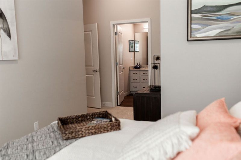 A cozy bedroom with a view into the bathroom, featuring neutral tones and modern decor.