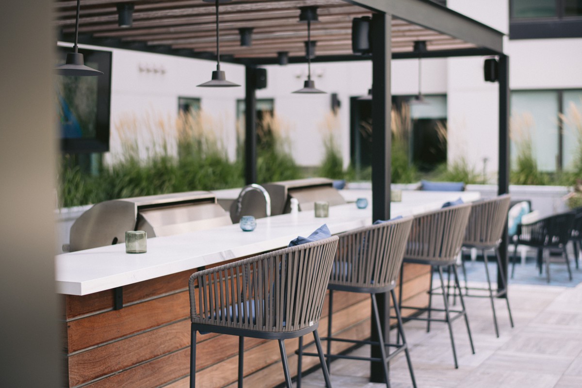 A stylish outdoor bar and dining area with modern furniture.