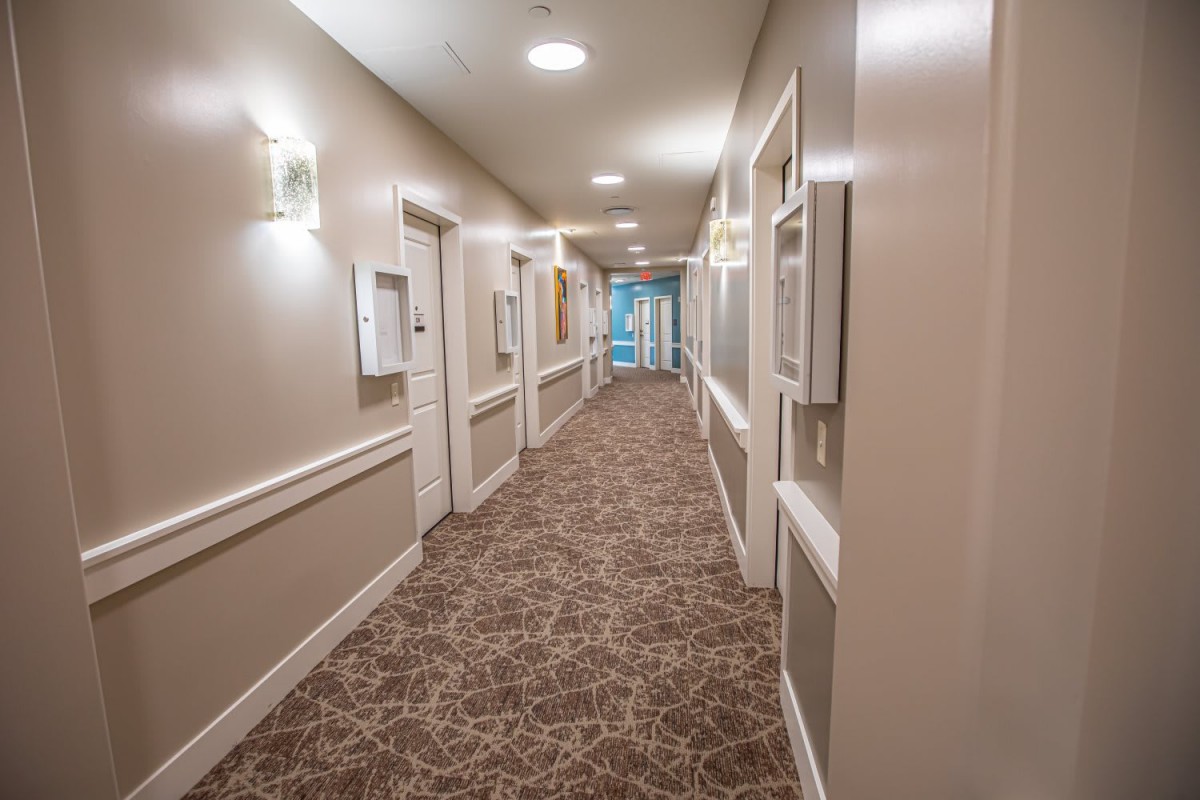 A well-lit hallway with carpet and multiple doors.