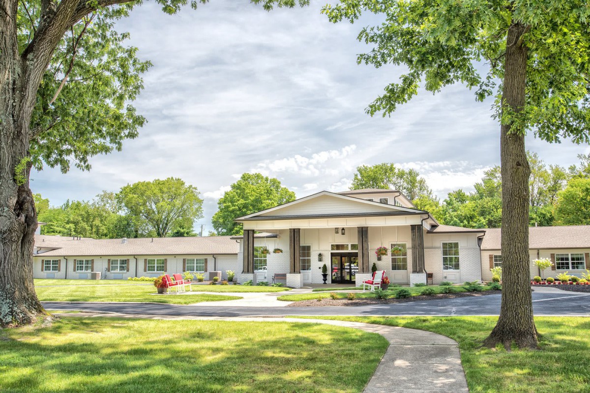 A picturesque view of a building with a welcoming entrance, surrounded by trees and a well-maintained lawn.