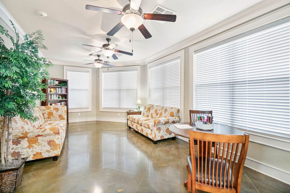 A bright and airy living room with modern furniture, large windows, and ceiling fans.