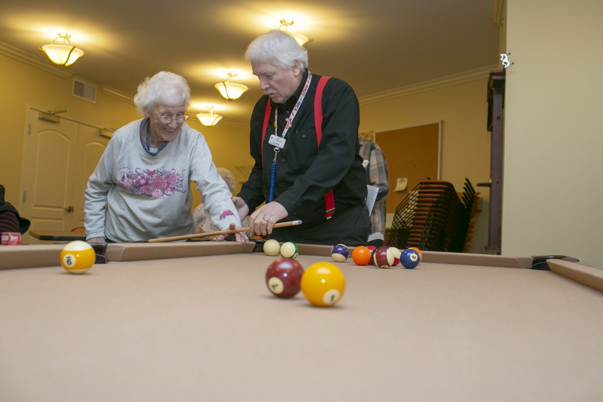 Two seniors enjoying a game of billiards together.