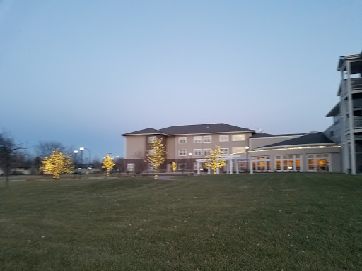 A modern building set against the evening sky, surrounded by lush green grass and illuminated trees.