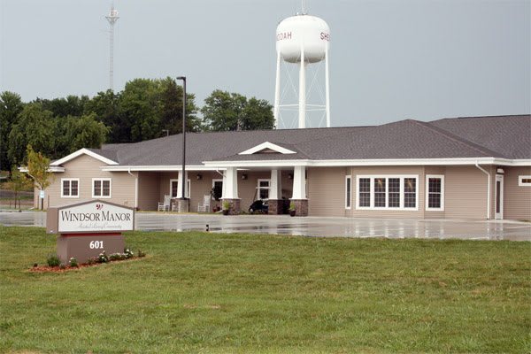 A community center building with a water tower in the background and a manicured lawn in front.