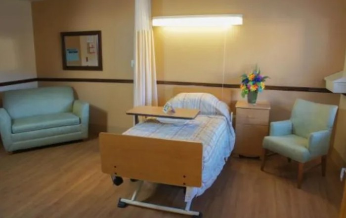A clean and tidy hospital room with a single bed and seating area.