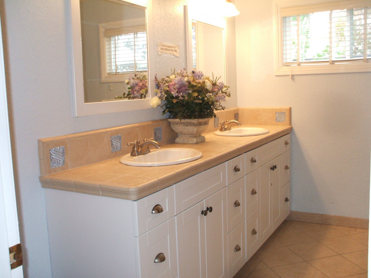 A well-lit bathroom with a double sink vanity and floral decoration.