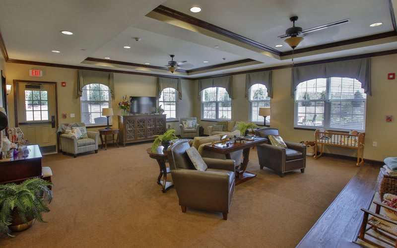 A cozy living room with comfortable seating, a television, and large windows.