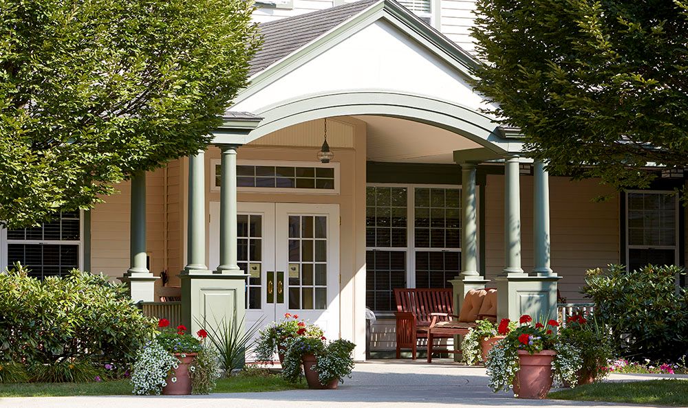 A welcoming porch with plants and outdoor seating at the entrance of a building.
