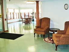 A bright indoor lounge area with comfortable chairs and a table near large windows.