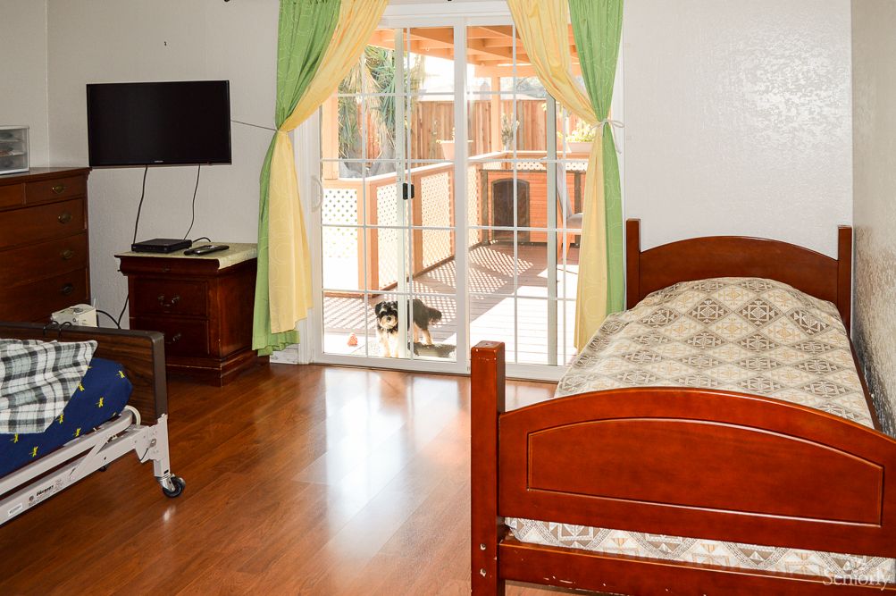 A cozy bedroom with a wooden bed, television, and sliding glass doors opening to an outdoor space.
