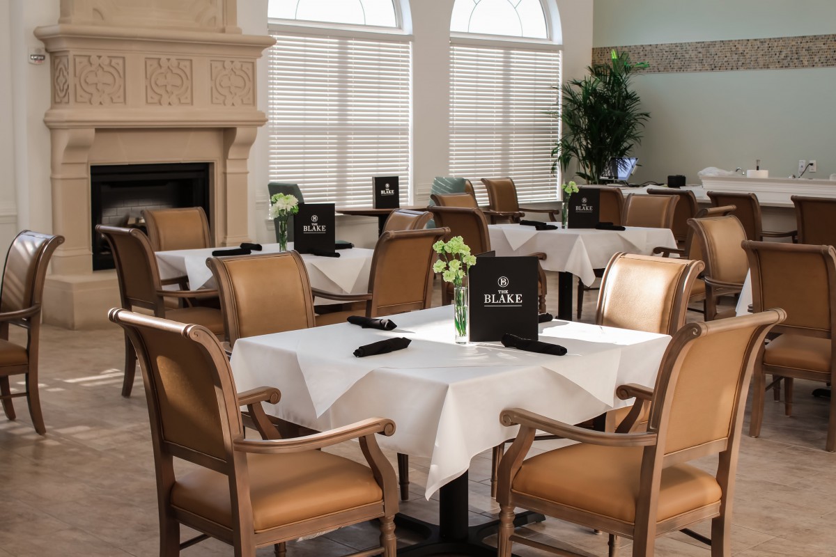 An elegant dining room with neatly set tables and chairs, featuring white tablecloths and a cozy ambiance.