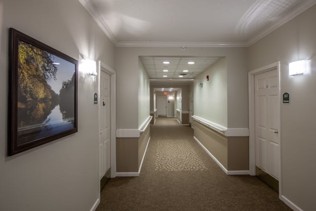 A long hallway in a building, featuring multiple doors and wall-mounted artwork.