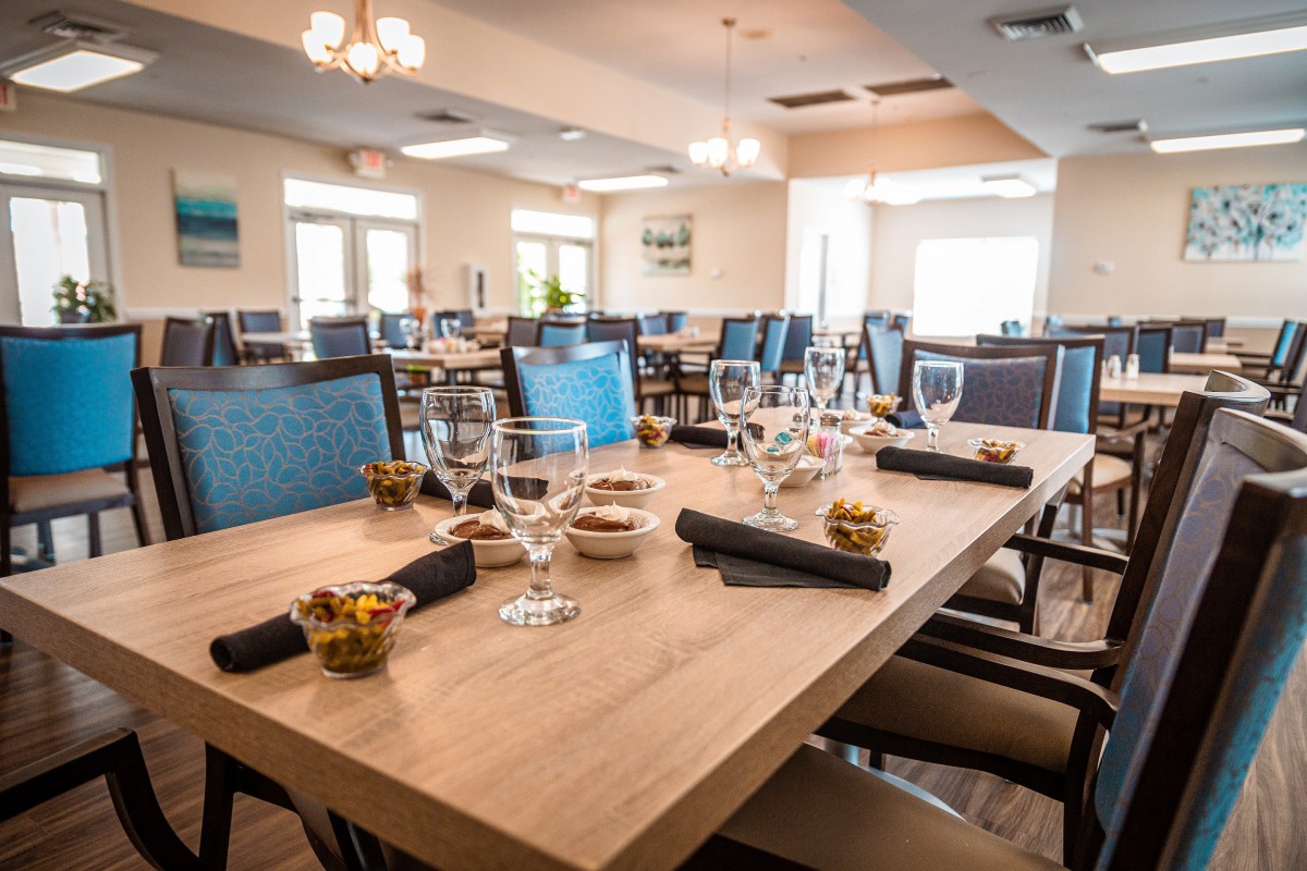 A modern restaurant dining room with neatly set tables, featuring glasses and napkins.