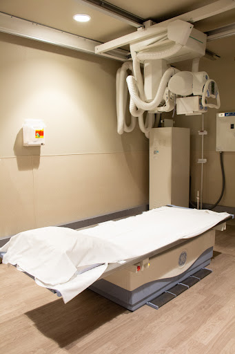 An x-ray room equipped with a patient bed and medical imaging equipment.