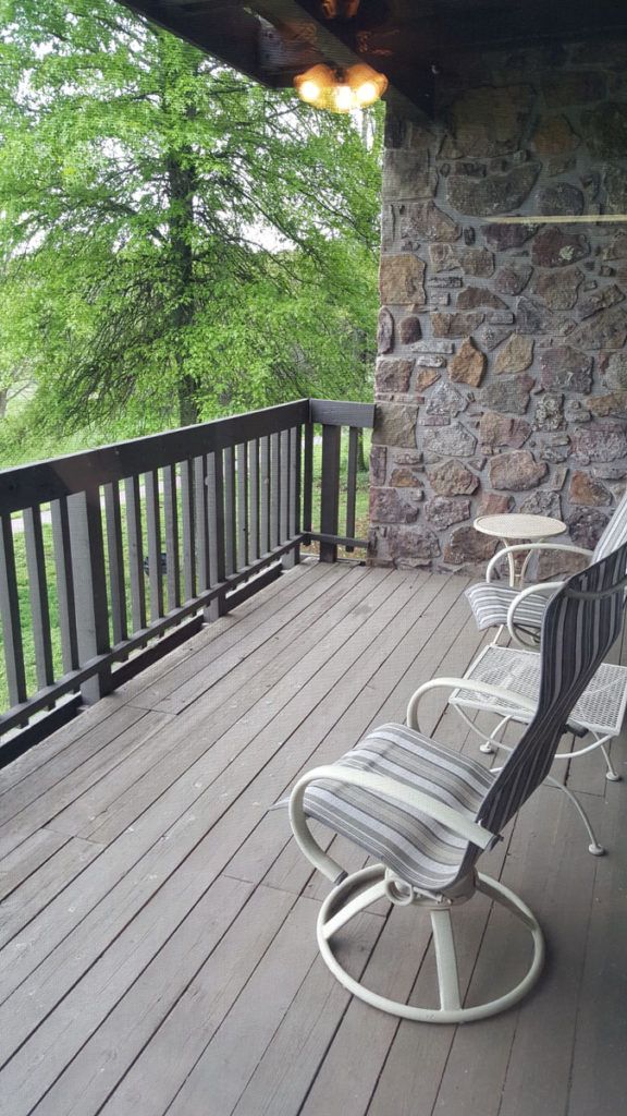 A scenic balcony with chairs overlooking a lush green view.