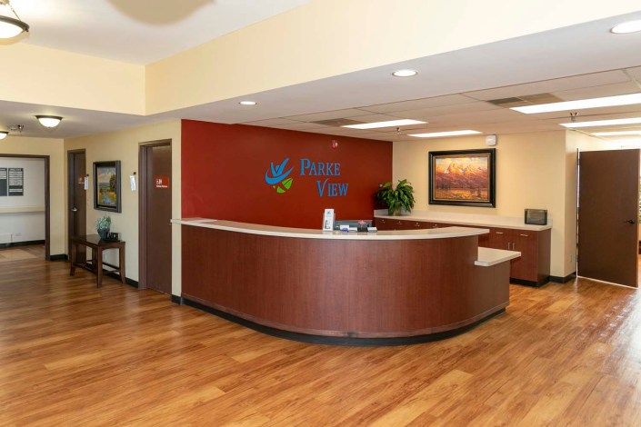 A modern reception area with a curved desk and wooden flooring.