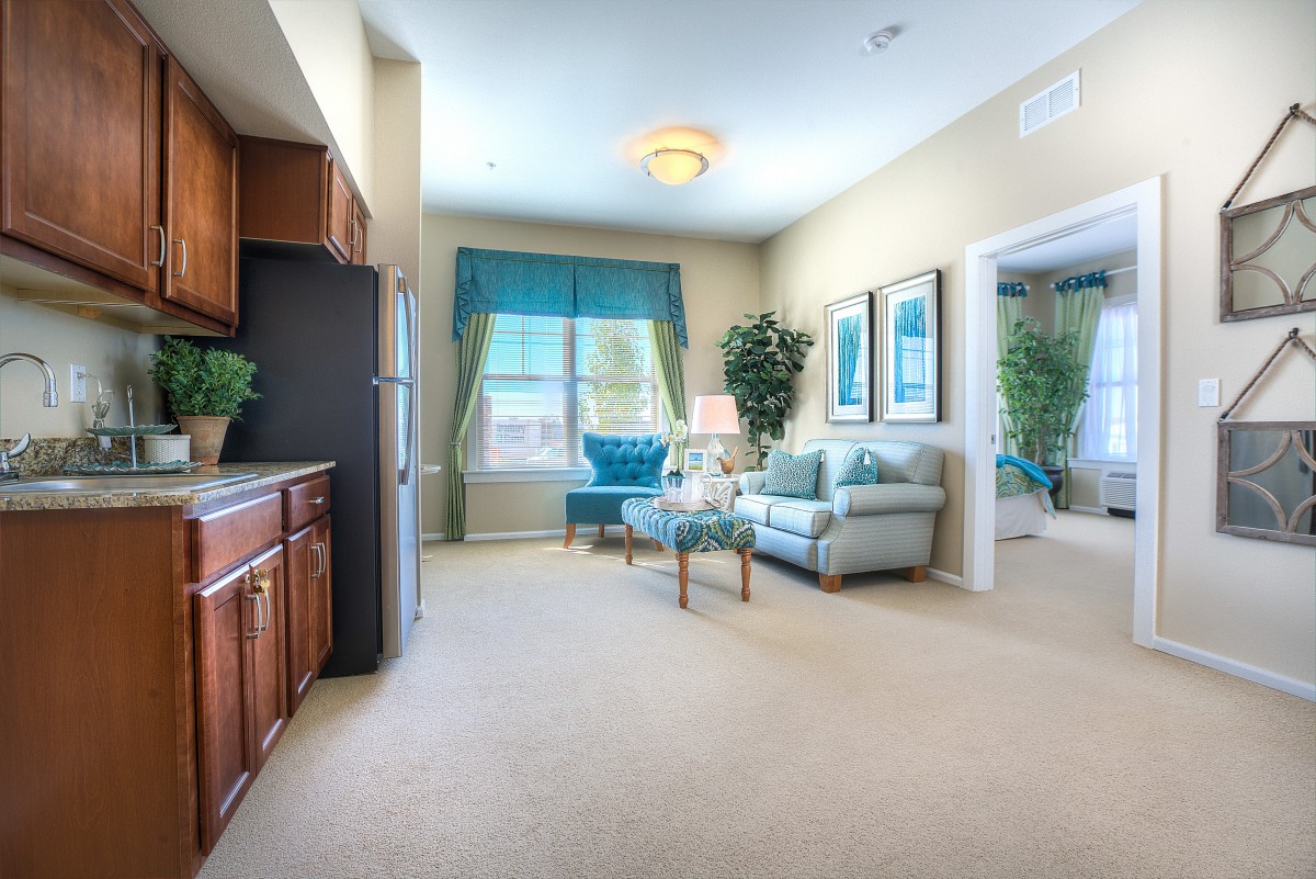 A cozy living room with a sofa, large window, and kitchenette area.