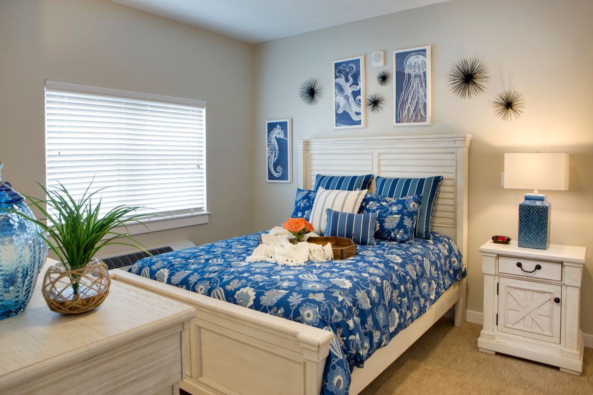 A cozy bedroom featuring blue and white decor with a neatly made bed and stylish artwork on the walls.