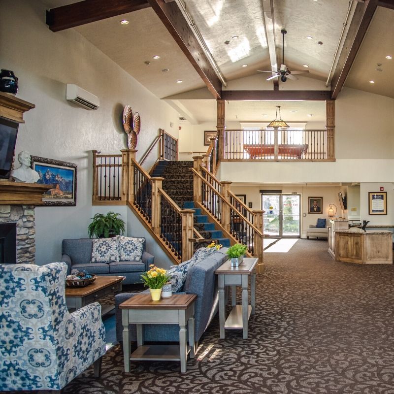 A spacious and well-lit living area featuring comfortable furniture, a staircase leading to a loft, and modern decor.