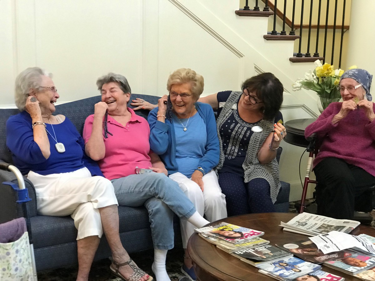 A group of seniors sharing a laugh together on a couch indoors.