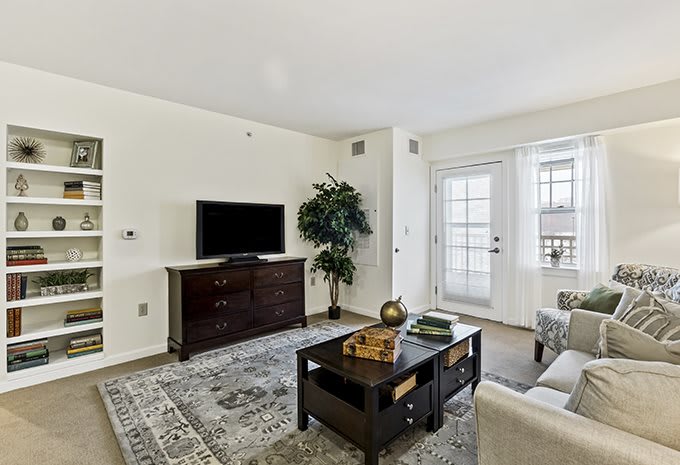A modern living room with stylish furniture, a TV setup, and abundant natural light.