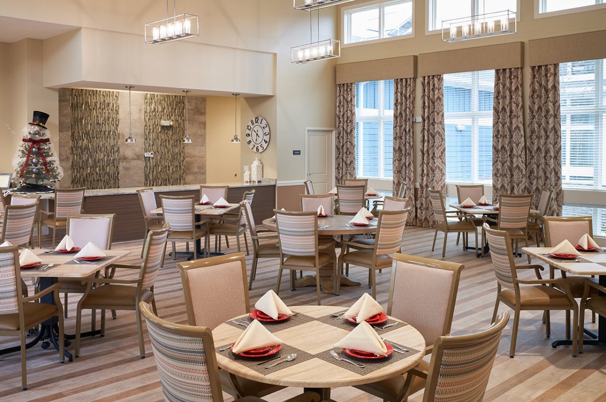 A well-lit dining area featuring neatly arranged tables with chairs and red napkins.