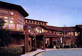 An exterior view of a hotel or resort building in the evening with illuminated lights.