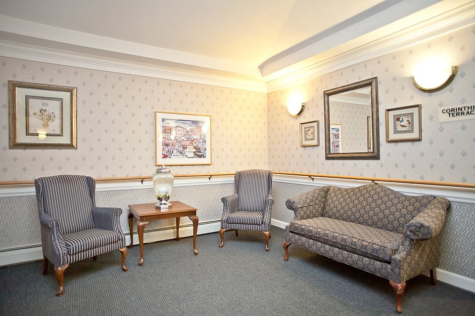 A cozy living room with classic furniture including a sofa, chairs, and a wooden table under warm lighting.