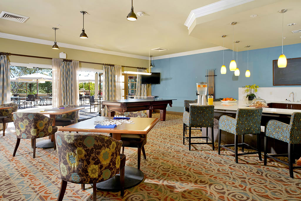 A spacious and modern living area featuring a pool table, comfortable seating, and a wall-mounted television.