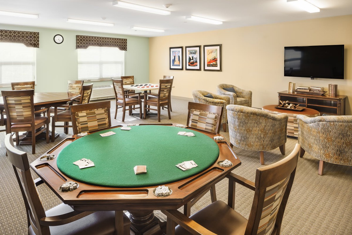 A recreation room featuring a poker table and comfortable seating areas.
