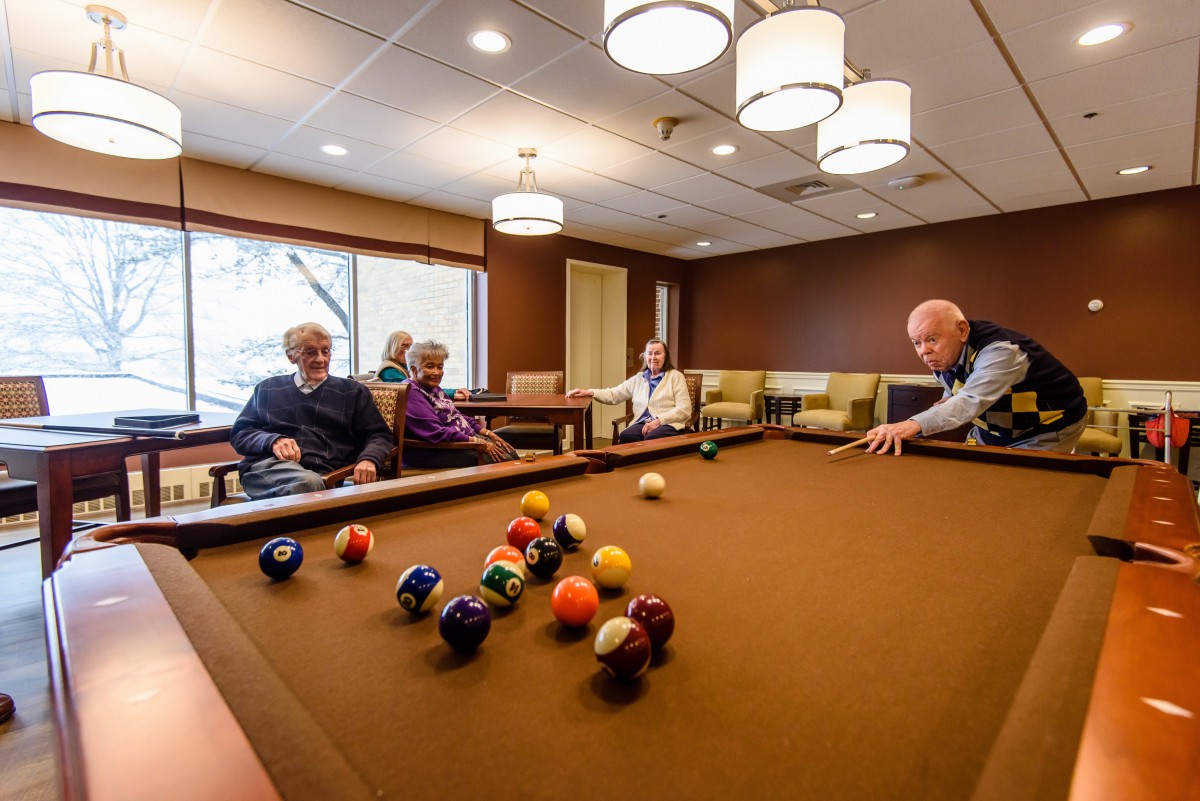 A group of seniors enjoying a game of billiards in a cozy indoor setting.