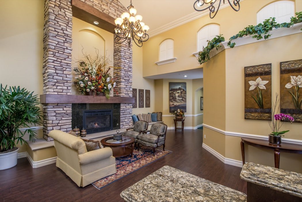 A cozy living room featuring a stone fireplace, elegant chandelier, and comfortable seating.