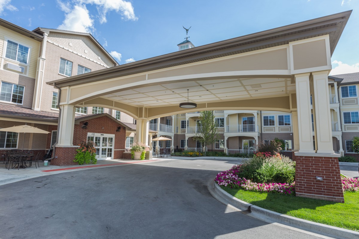 A welcoming hotel entrance with neatly maintained landscaping and a covered driveway.
