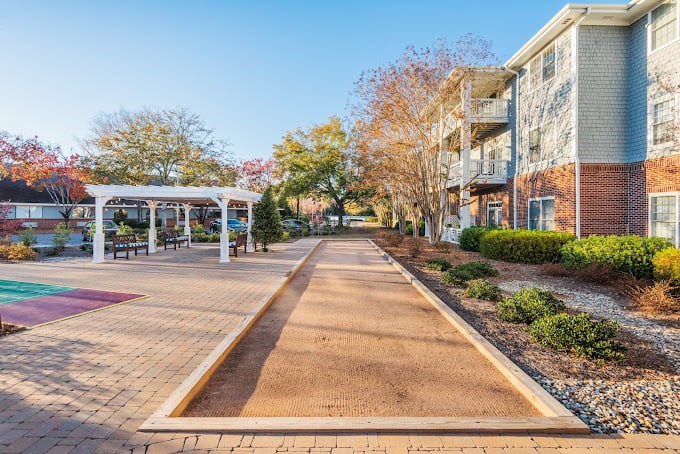 An outdoor walkway featuring a bocce court and landscaped gardens in a residential area.