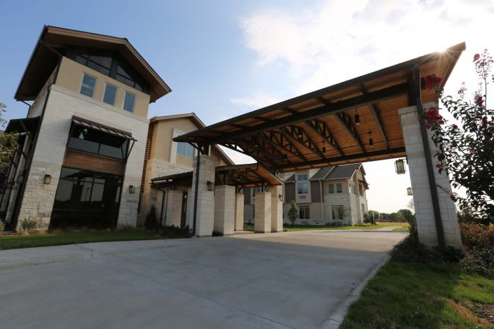 A modern residential building with a covered entrance and spacious driveway.