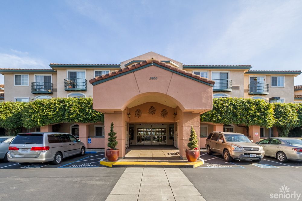 A hotel entrance with cars parked outside on a sunny day.