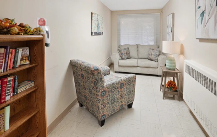 A cozy living room with a sofa and an armchair arranged around a small lamp on a side table.