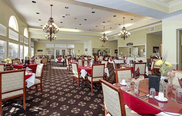 An elegant dining room with red tablecloths and ornate chandeliers.
