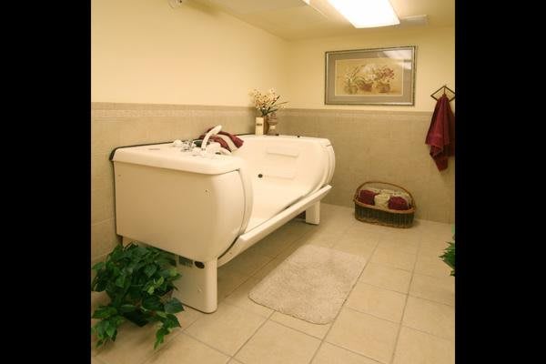 A spacious bathroom featuring a modern bathtub, decorative plants, and a neatly arranged towel rack.