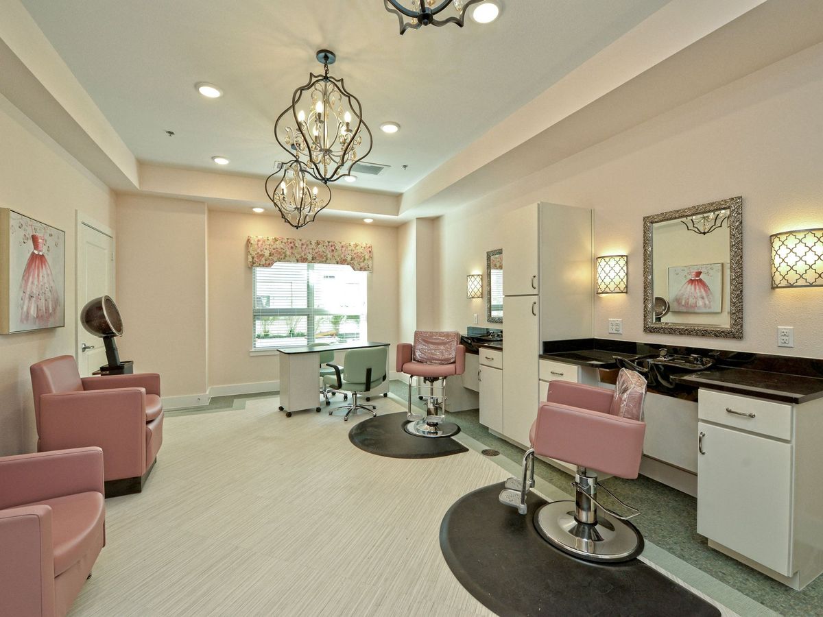 A beautifully designed beauty salon with elegant chandeliers and pink chairs.