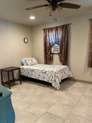 A tidy bedroom with a single bed, side table, and curtains.