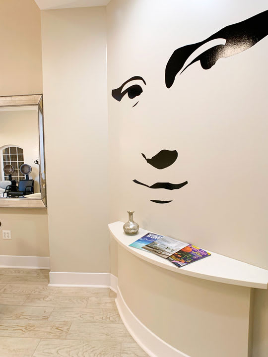 A modern, minimalist waiting area featuring wall art and a small table with magazines.