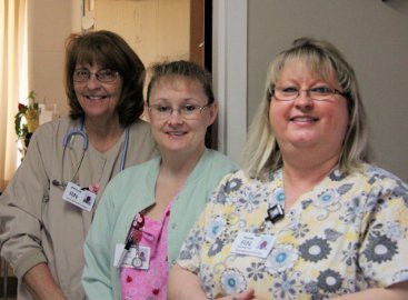 Three nurses smiling in a hospital setting.