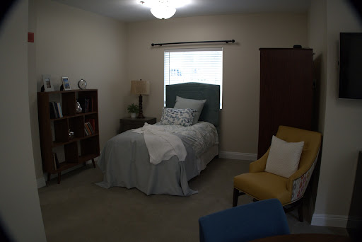 A cozy and well-decorated bedroom with a single bed, a reading chair, and a bookshelf.