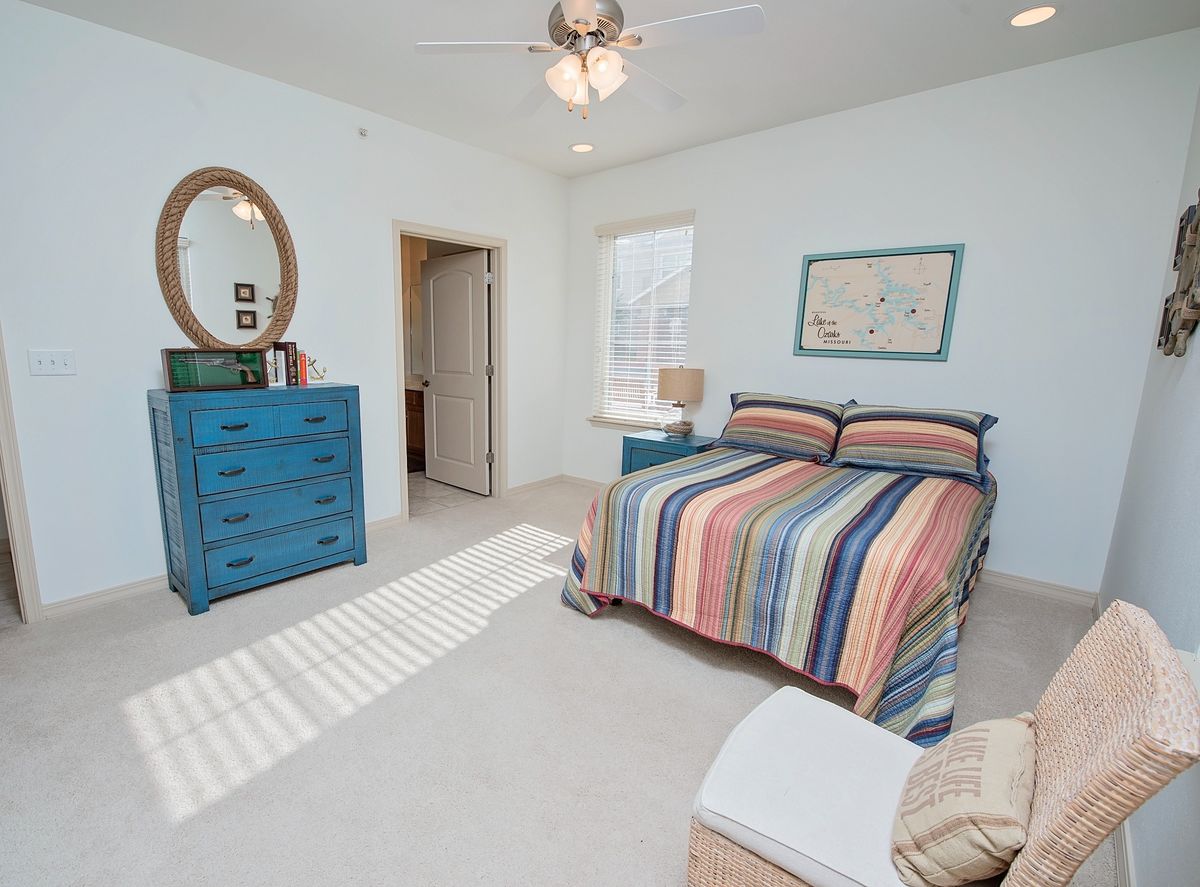 A cozy bedroom with a striped bedspread, blue dresser, and soft lighting.