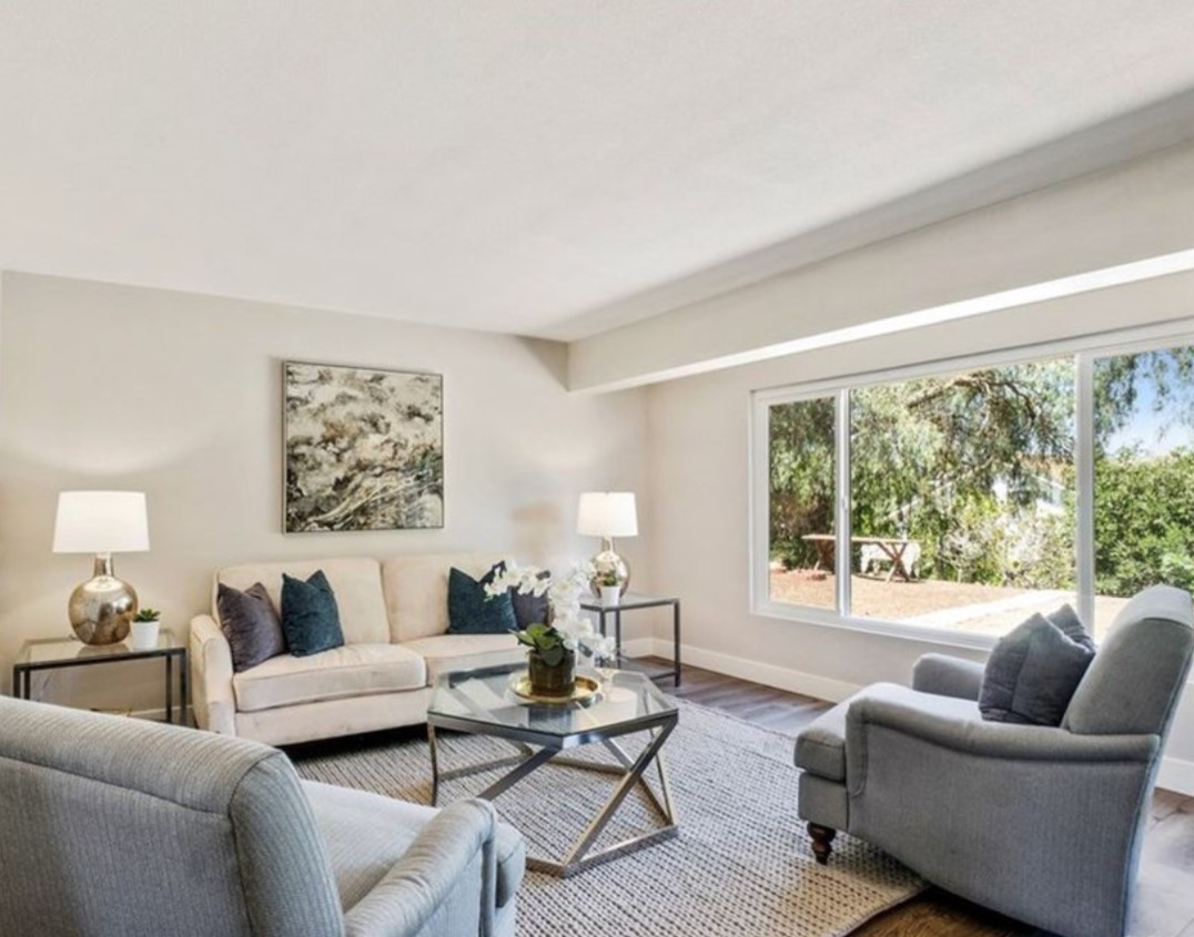 A bright and spacious living room with modern furniture and a large window overlooking greenery.