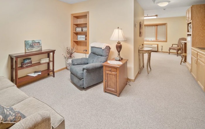 A cozy living room with a recliner, side table, and bookshelf.