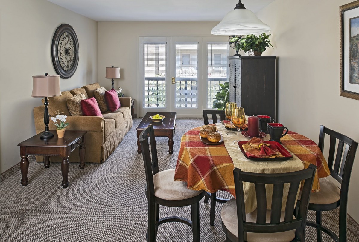 A cozy living room with a dining area featuring a table set for a meal, complemented by a comfortable sofa and homey decor.