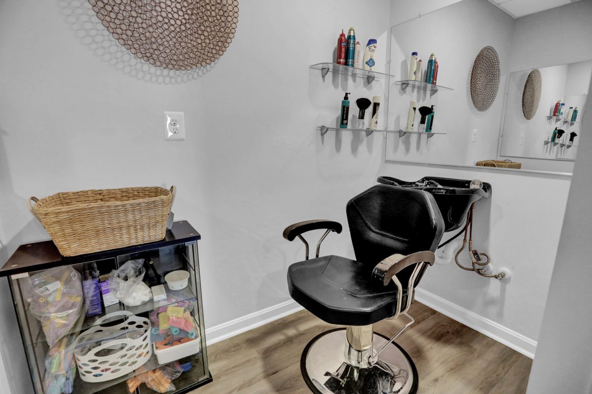A modern salon setup featuring a barber chair and neatly arranged hair products on shelves.